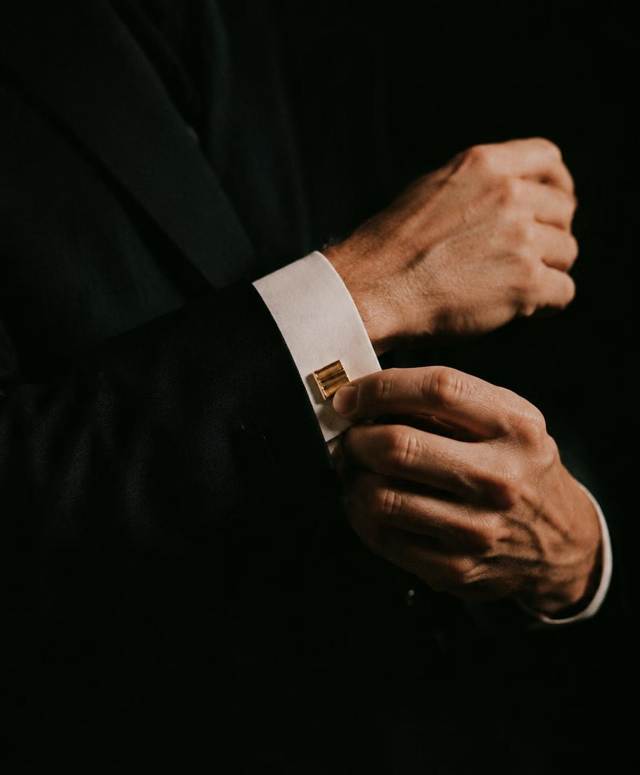 Hands adjusting a shirt cuff fastened with a gold link
