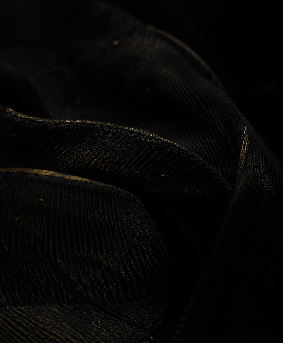 Folded dark fabric catching a thin line of gold light